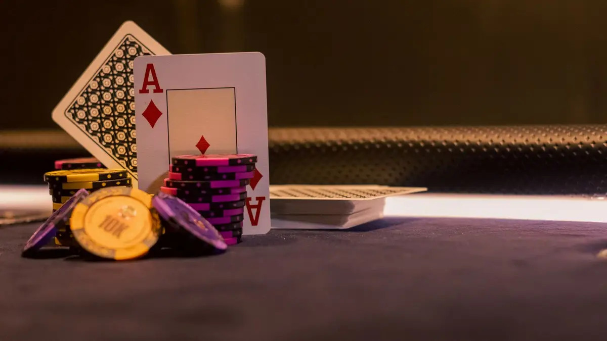 An ace of diamonds propped against stacks of gold and purple chips